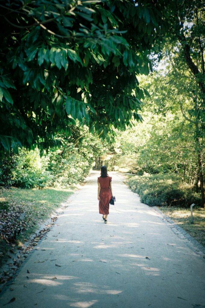 Une femme en robe rouge marche sur un chemin entouré de verdure